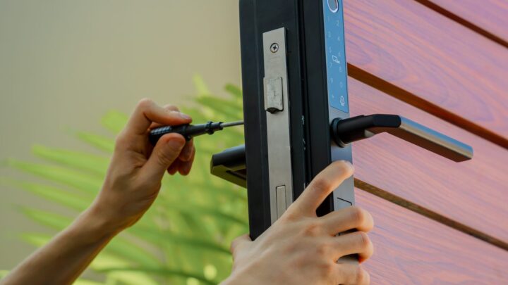 Driving screws into a newly fitted electronic deadbolt on a wooden door