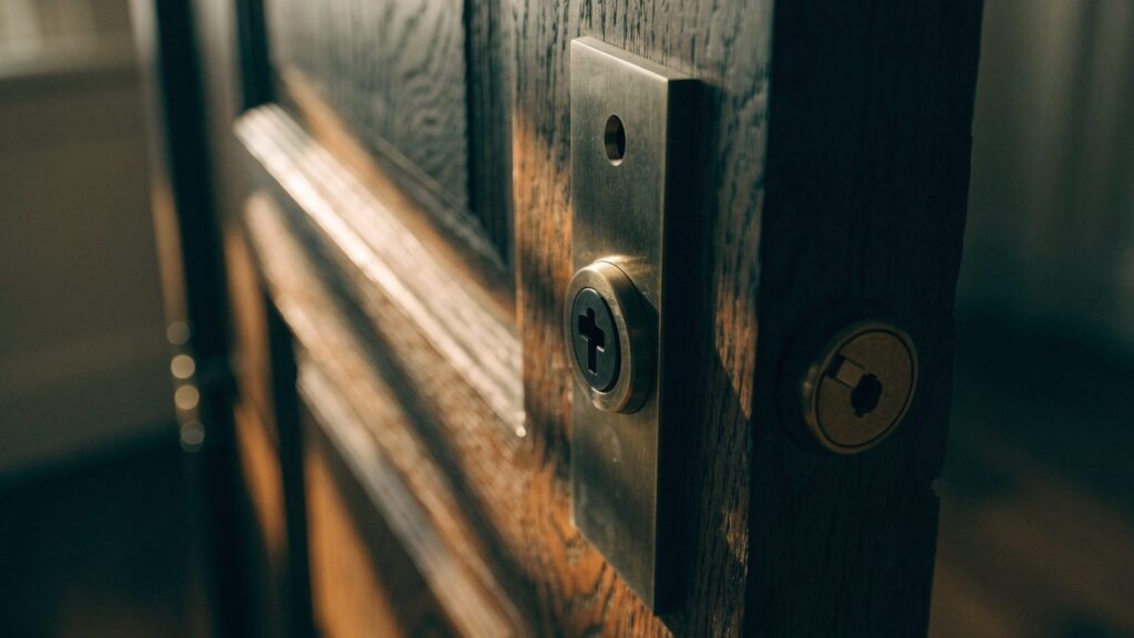 Interior face of a deadbolt fitted with a keyed cylinder instead of a thumbturn on a dark stained wood door