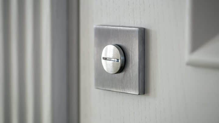 The interior thumbturn of a deadbolt on a white door, close up