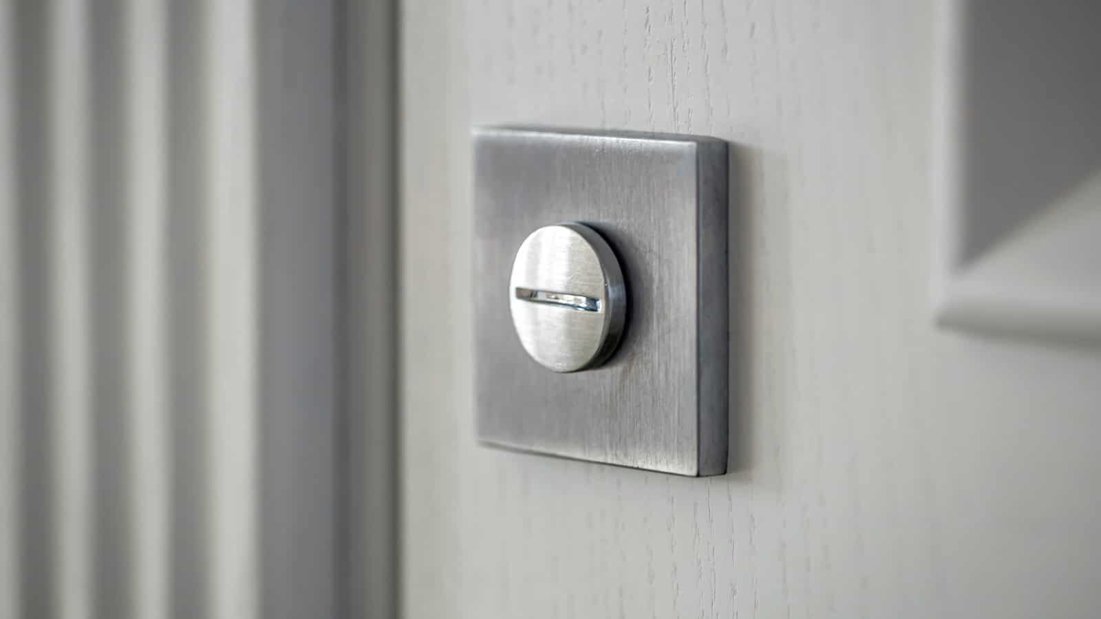 The interior thumbturn of a deadbolt on a white door, close up
