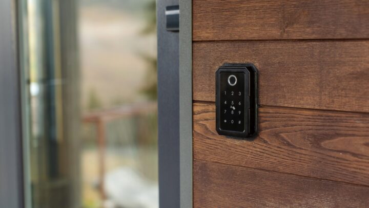 A keyless entry keypad mounted on a wooden frame beside a sliding glass door