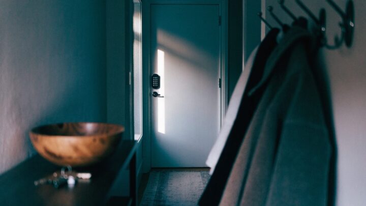 An electronic keypad deadbolt on a white front door, seen from inside an entry hall in morning light
